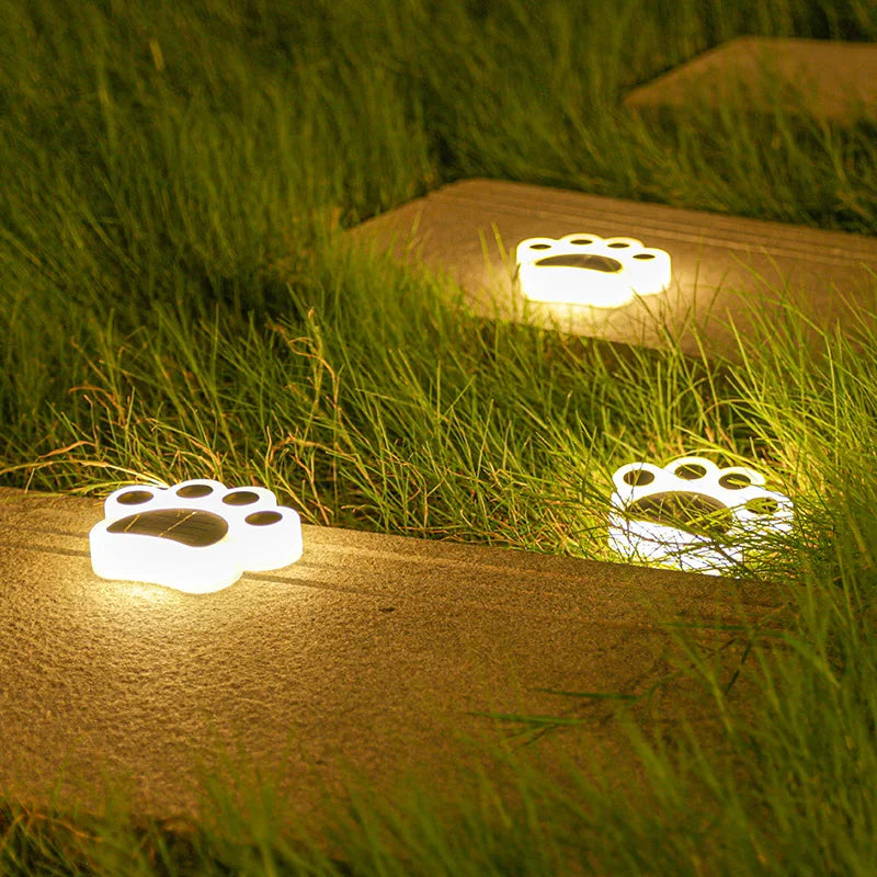 Paw print garden lights glowing along a path at dusk